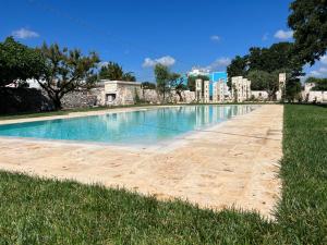 a swimming pool in the middle of a grass field at Agriturismo Masseria Calongo in Cisternino