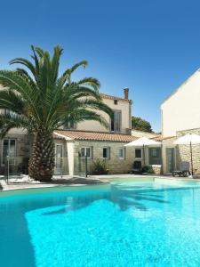 a swimming pool with a palm tree in front of a house at Hôtel Le Square in Saint-Pierre-dʼOléron