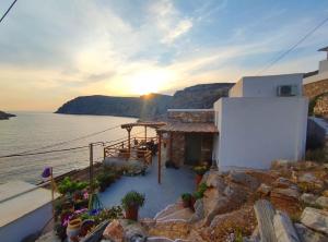 a building on the side of the water with the sunset at Cheronissos View in Sifnos