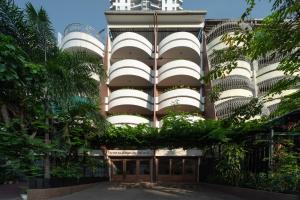un edificio con palmeras delante en Stay Plus Hotel Bangkok en Bangkok