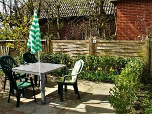 a table and chairs with a green and white umbrella at Ohl Dörp 10, Wrixum auf der Insel Föhr in Wrixum