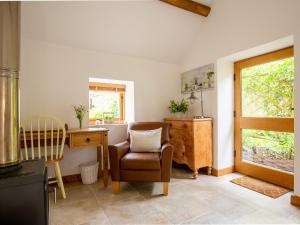 a living room with a chair and a desk and a window at High Pump Cottage in Chipping Campden