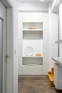 a white kitchen with white shelves and a door at Central Athenian 1BR Apartment in Athens