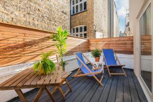 2 Stühle und ein Holztisch auf dem Balkon in der Unterkunft StayLux Kensington in London