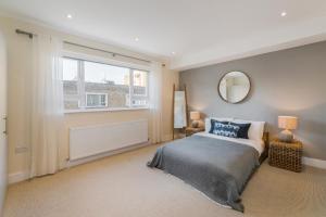 Schlafzimmer mit einem Bett, einem Fenster und einem Spiegel in der Unterkunft StayLux Kensington in London