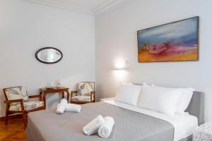 a white bedroom with a bed and two chairs at Central Athenian 1BR Apartment in Athens