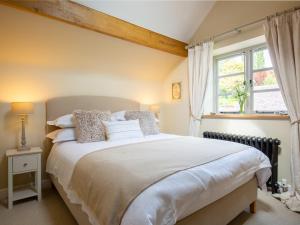 Un dormitorio con una cama grande y una ventana en High Pump Cottage, en Chipping Campden