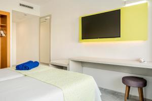 マガルフにあるGlobales Torrenovaのベッド1台、壁掛けテレビが備わるホテルルームです。