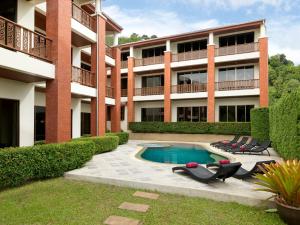 ein Apartmentgebäude mit einem Pool und Liegestühlen in der Unterkunft Sun Hill Hotel Patong in Patong Beach
