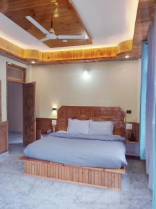 a bedroom with a large bed with a wooden headboard at Delight Homestay Kasol in Kasol