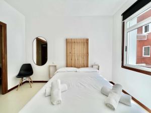 a white bedroom with a large bed and a window at Green Door Coruña in A Coruña