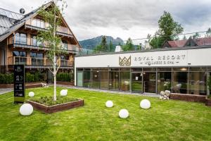 a building with a yard with white balls on the grass at Apartamenty Royal Resort & Spa in Zakopane