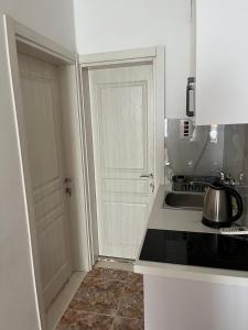 a white kitchen with a sink and a door at Imperator Apartments in Ulcinj