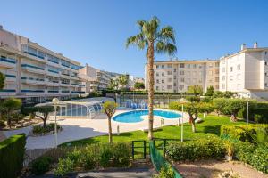 een appartementencomplex met een zwembad en een palmboom bij Estrella 2 1a Spaniahome in L'Alfas del Pi