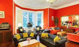 a living room with red walls and black leather furniture at Harvieston Hall in Gorebridge