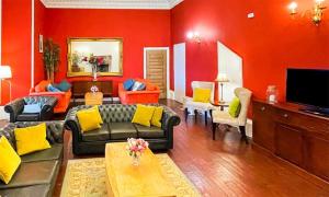 a living room with red walls and yellow pillows at Harvieston Hall in Gorebridge
