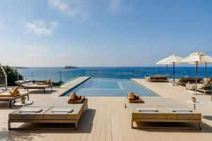 a swimming pool with tables and chairs and the ocean at ME Ibiza - The Leading Hotels of the World in Santa Eularia des Riu
