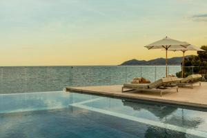 a swimming pool with two lounge chairs and an umbrella at ME Ibiza - The Leading Hotels of the World in Santa Eularia des Riu