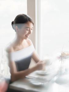 una mujer con un vestido blanco sentada en una mesa en The Ritz-Carlton Shanghai, Pudong, en Shanghái