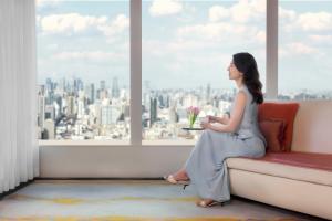 una mujer sentada en un sofá mirando por la ventana en The Ritz-Carlton Shanghai, Pudong en Shanghái