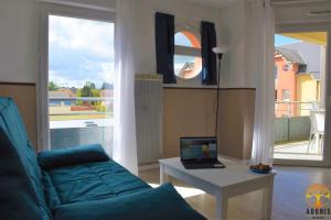 a living room with a couch and a laptop on a table at Adonis Grandcamp - Résidence Les Isles De Sola in Grandcamp-Maisy