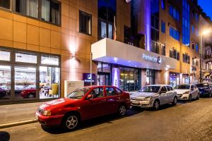 two cars parked on a street in front of a building at Premier Inn Frankfurt City Centre in Frankfurt