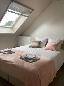 een slaapkamer met 2 bedden met kussens en een raam bij Hill44 in Zonnebeke