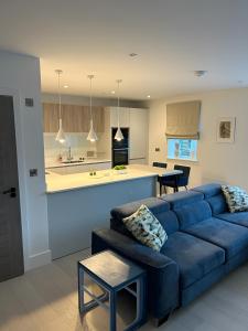 ニューキーにあるBeachside Apartmentの青いソファとキッチンのあるリビングルーム