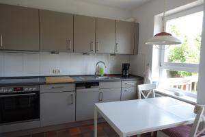 eine Küche mit weißen Schränken, einem Tisch und einem Fenster in der Unterkunft Ferienwohnung im Kieler Süden in Kiel