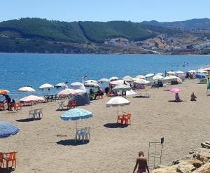 Ein Strand mit einem Haufen Regenschirme und Menschen darauf. in der Unterkunft Azla beach in Azla