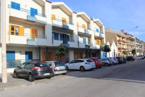 a row of cars parked in front of a building at Ti Laura Praia in Praia da Barra