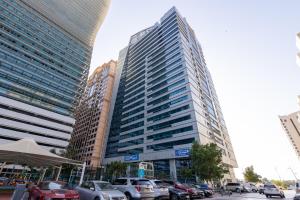 a tall building with cars parked in a parking lot at HUGE 2 Bedroom Apartment Beach Front (City View) in Abu Dhabi