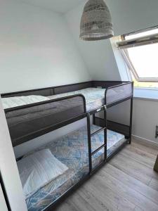 Ce dortoir comprend 2 lits superposés et une fenêtre. dans l'établissement Studio cosy vue mer et campagne, à Villers-sur-Mer