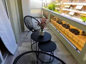 2 sedie e un tavolo con un vaso di fiori sul balcone di AGORA luxury APARTMENT 3 a Loutraki