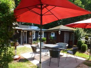 a table and chairs with a red umbrella on a patio at Ferienhaus Tanneneck in Pottum