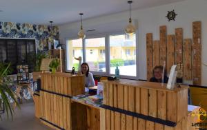 two women sitting at a counter in a store at Adonis Grandcamp - Résidence Les Isles De Sola in Grandcamp-Maisy