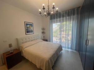 una camera con letto, finestra e lampadario a braccio di Casa Isotta a Riva Ligure