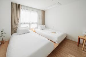 2 camas blancas en una habitación con ventana en Urbanstay Boutique Ikseon en Seúl