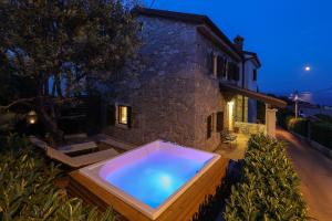 una vasca idromassaggio di fronte a una casa di notte di Villa Fani with Jacuzzi a Ičići