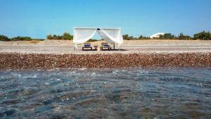 ein Zelt und Stühle am Strand neben dem Wasser in der Unterkunft Beachfront Villa SeaShell Superior in Gennadi