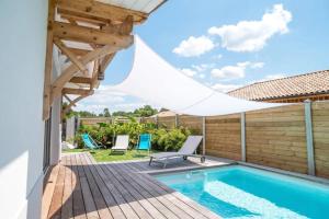 un patio avec une piscine et une terrasse en bois dans l'établissement La villa Sirelis piscine et spa, à Gujan-Mestras