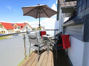 eine Terrasse mit einem Tisch und einem Sonnenschirm auf dem Balkon in der Unterkunft Haus Sonne - FeWo 08 in Thiessow