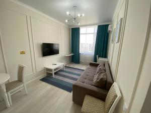 un soggiorno con divano e TV di Alau Apartments a Astana