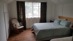a bedroom with a bed and a chair and a window at Crafty Coal Stove in Pietermaritzburg