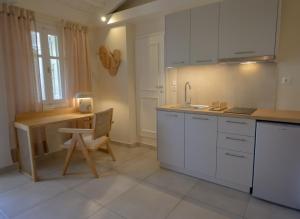 una cucina con armadi bianchi, tavolo e scrivania di Oikies Small Elegant Houses a Mytilini