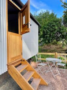 una casa exterior de madera con 2 sillas y una mesa en The Hereford Hut, Charming 1 bedroom Shepherds Hut en Callow