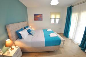 a bedroom with a large bed with blue curtains at Villa Eoli Corfu in Ágios Prokópios