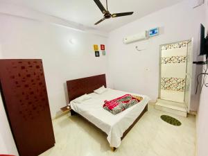 a small room with a bed with a ceiling fan at Rita Shree Homestay At Ayodhya Highway in Sultānpur