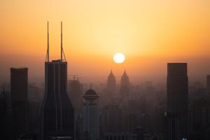 a city skyline with the sun setting in the sky at The Ritz-Carlton Shanghai, Pudong in Shanghai