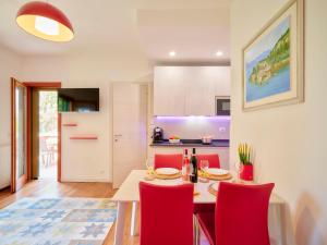 kuchnia i jadalnia ze stołem i czerwonymi krzesłami w obiekcie Appartamento Noal w mieście Bardolino